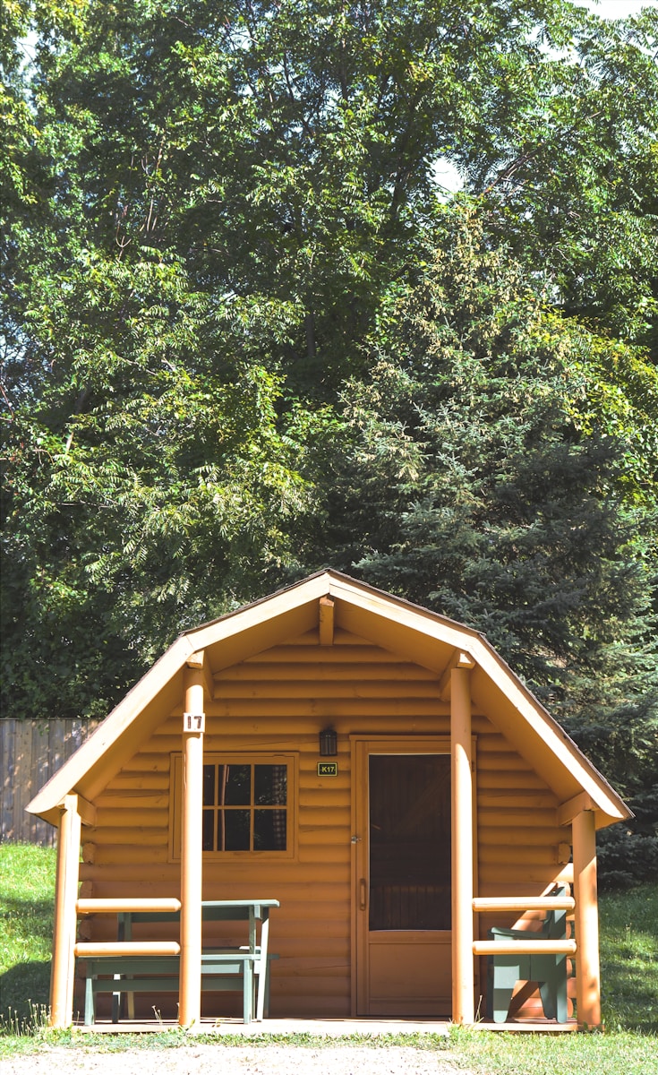 brown wooden house surrounded by green trees during daytime