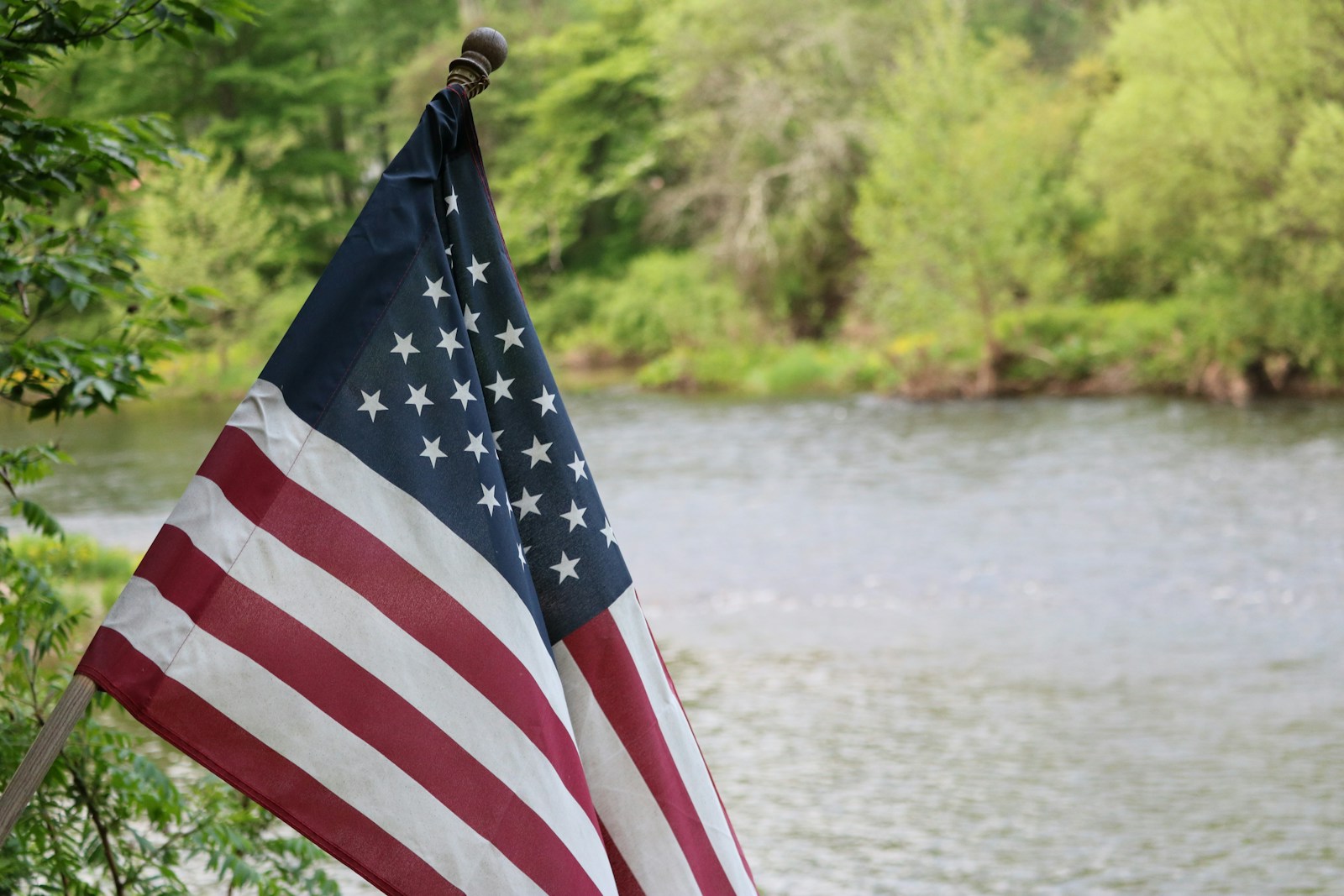 us a flag on pole near body of water during daytime